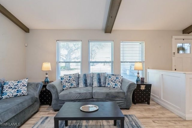 living room featuring beamed ceiling, light wood-type flooring, and a wealth of natural light