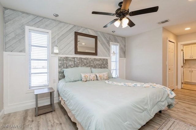 bedroom featuring multiple windows, light wood-type flooring, a closet, and ceiling fan