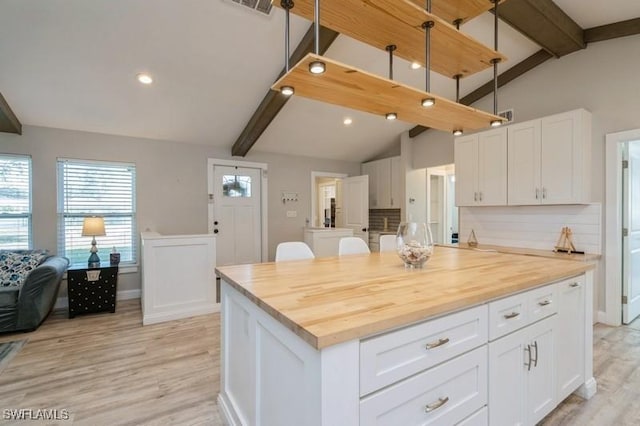 kitchen with butcher block countertops, white cabinets, and backsplash