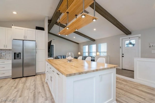 kitchen with white cabinetry, a center island, vaulted ceiling with beams, stainless steel fridge, and light wood-type flooring