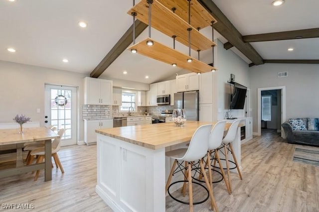 kitchen with tasteful backsplash, stainless steel appliances, light hardwood / wood-style flooring, white cabinets, and a kitchen island