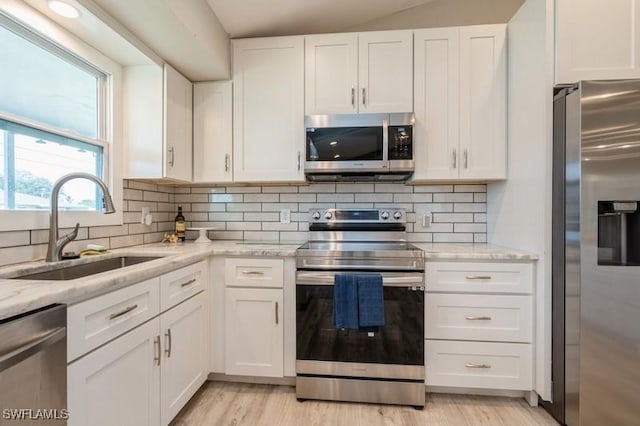 kitchen with light stone countertops, sink, white cabinetry, and stainless steel appliances