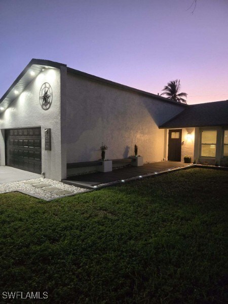 property exterior at dusk with a garage and a lawn