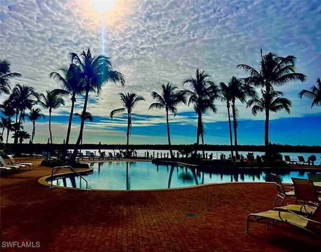 pool at dusk featuring a water view