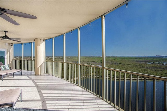 balcony featuring a water view and ceiling fan