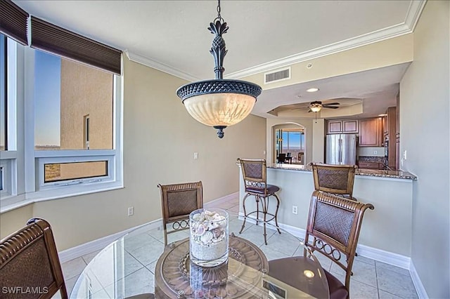 dining area featuring ceiling fan, crown molding, and light tile patterned floors