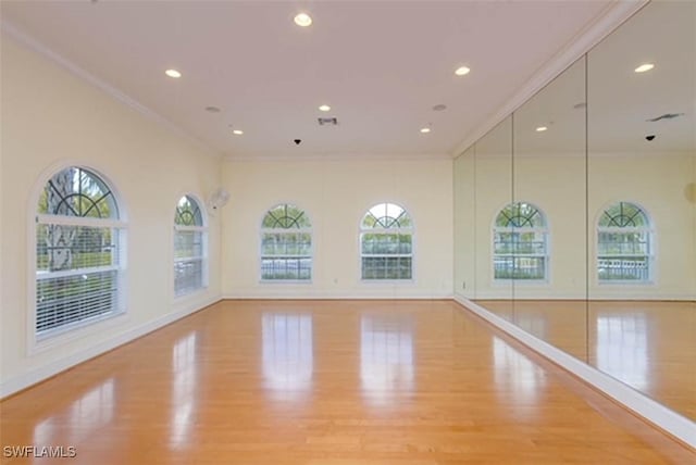 exercise area with light hardwood / wood-style flooring and ornamental molding