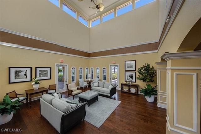 living room featuring a towering ceiling, dark hardwood / wood-style floors, and crown molding