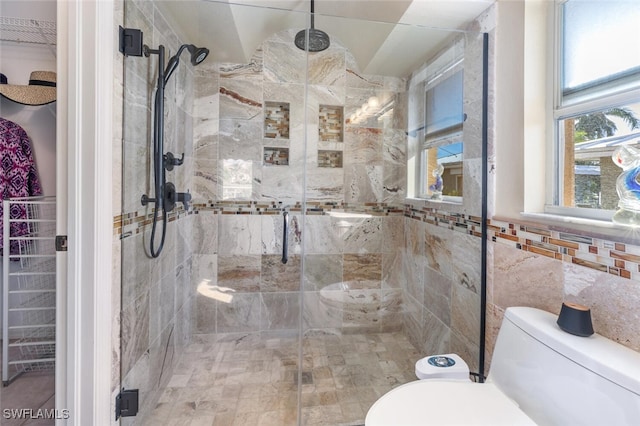 bathroom featuring a shower with shower door, tile walls, and toilet