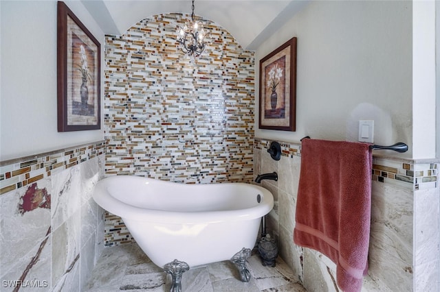 bathroom featuring a bathtub, lofted ceiling, tile walls, and an inviting chandelier