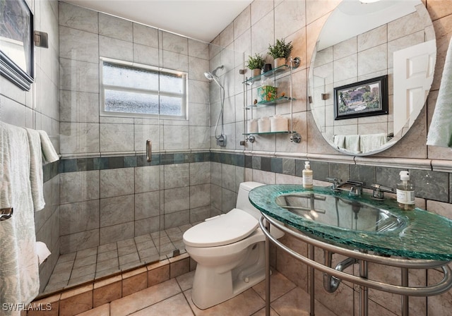 bathroom with backsplash, tile patterned floors, a shower with door, tile walls, and toilet