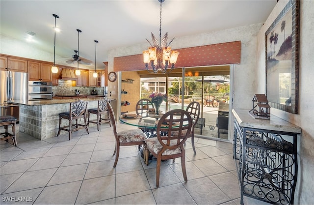 dining space with ceiling fan with notable chandelier, vaulted ceiling, and light tile patterned flooring