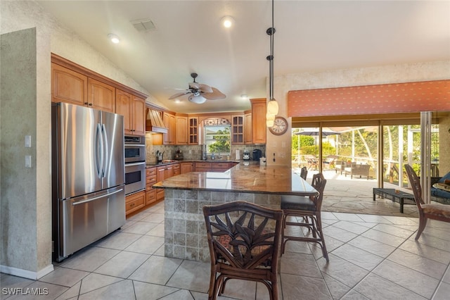 kitchen featuring a kitchen breakfast bar, kitchen peninsula, a healthy amount of sunlight, and appliances with stainless steel finishes