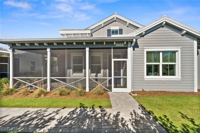 back of property featuring a sunroom and a yard