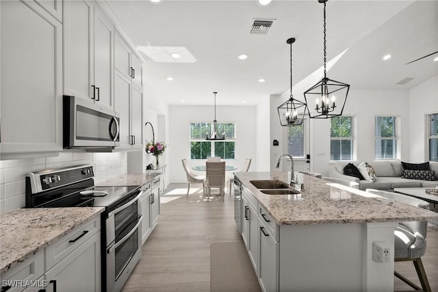 kitchen featuring white cabinets, stainless steel appliances, and an island with sink