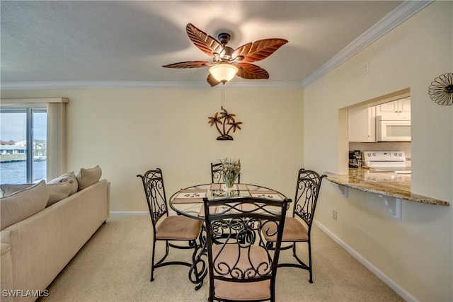 dining room featuring light carpet, ornamental molding, a water view, and baseboards