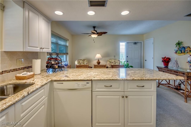 kitchen featuring visible vents, dishwasher, light stone counters, a peninsula, and white cabinetry