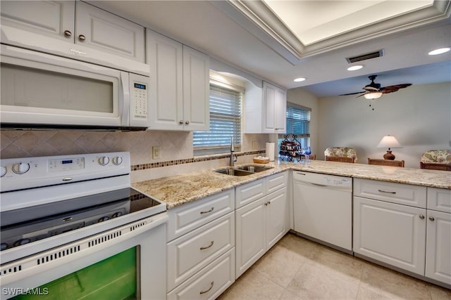 kitchen featuring visible vents, a sink, a ceiling fan, white appliances, and decorative backsplash