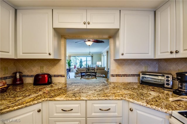 kitchen with white cabinets, light stone countertops, ceiling fan, and decorative backsplash