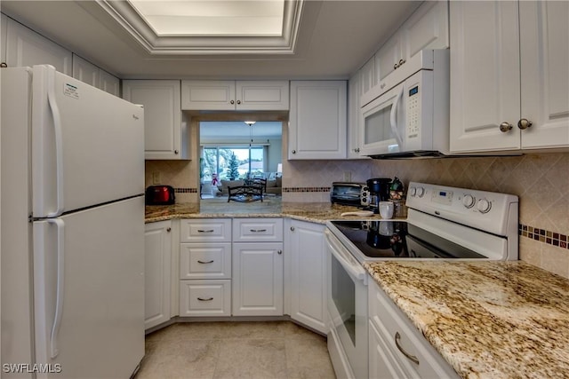 kitchen featuring white appliances, white cabinetry, light stone countertops, tasteful backsplash, and a raised ceiling