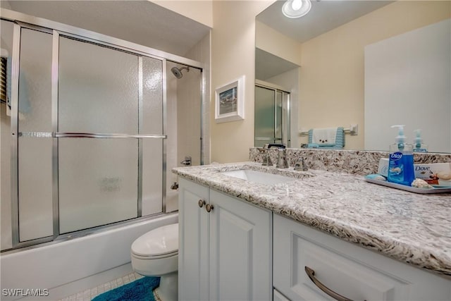 bathroom featuring tile patterned flooring, toilet, vanity, and bath / shower combo with glass door