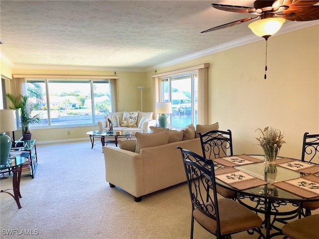 living room with baseboards, a textured ceiling, crown molding, ceiling fan, and light colored carpet