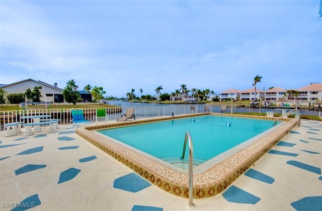 community pool featuring a patio area, a water view, and fence