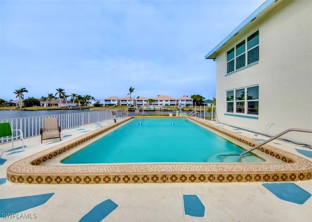 community pool featuring a patio, a water view, and fence