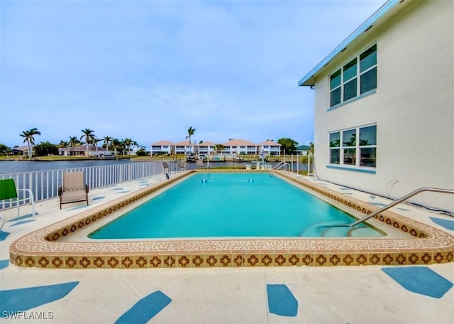 community pool with a water view, a patio, and a residential view