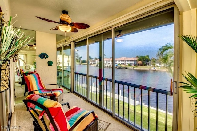 balcony with a water view and a ceiling fan