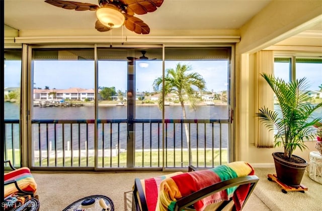 sunroom / solarium featuring a water view and ceiling fan