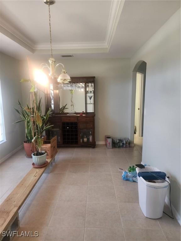 tiled dining area with a notable chandelier, crown molding, and a tray ceiling