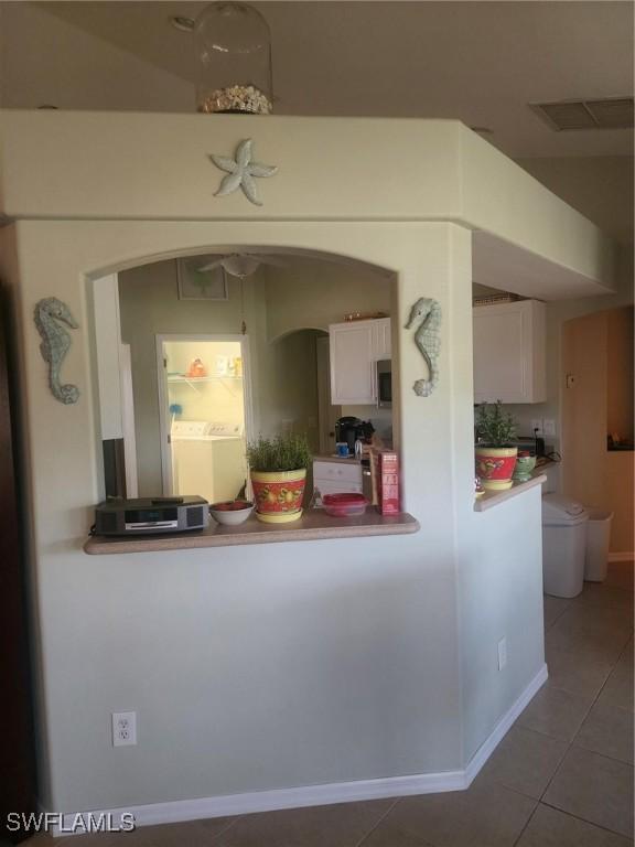 kitchen with washer / clothes dryer, tile patterned floors, and white cabinetry