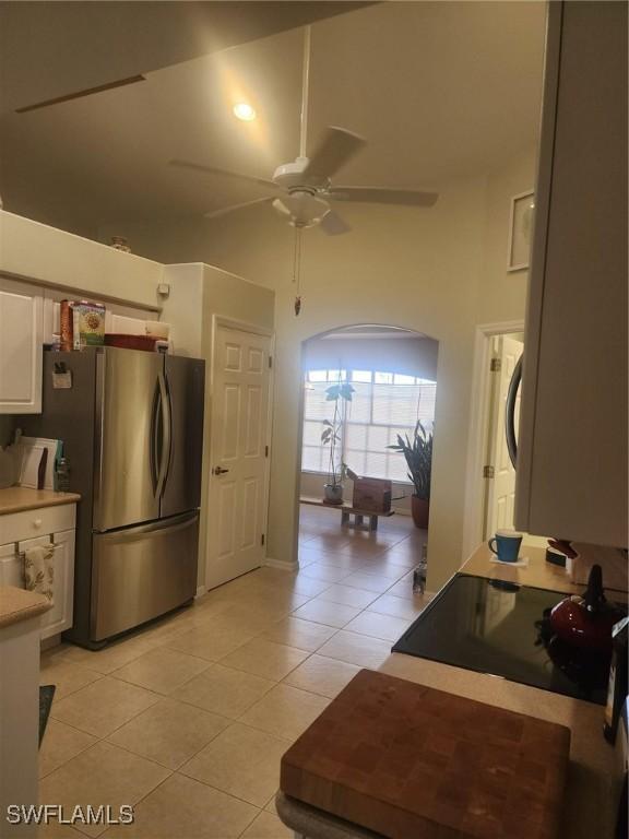 kitchen featuring ceiling fan, stainless steel fridge, white cabinetry, and light tile patterned floors