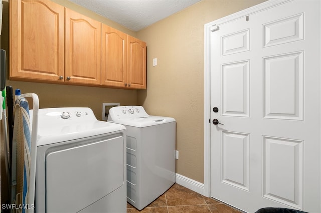 laundry area featuring dark tile patterned flooring, cabinets, a textured ceiling, and washing machine and clothes dryer