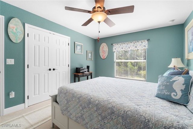 bedroom with a closet, ceiling fan, and light colored carpet