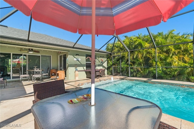 view of swimming pool featuring glass enclosure, ceiling fan, and a patio area