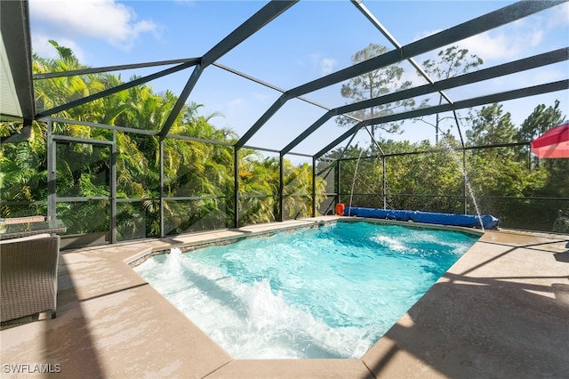 view of pool with glass enclosure and a patio