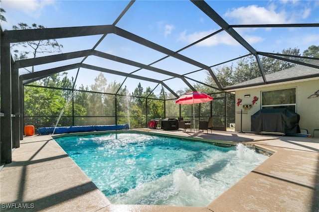 view of pool with glass enclosure, a patio, and grilling area