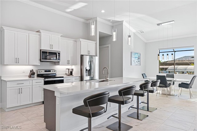 kitchen featuring a center island with sink, decorative light fixtures, white cabinets, and stainless steel appliances