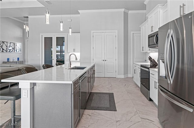 kitchen with white cabinets, appliances with stainless steel finishes, a kitchen island with sink, and sink