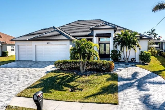 view of front of home with french doors, a front yard, and a garage