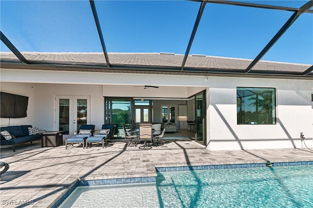 back of house with glass enclosure, ceiling fan, french doors, an outdoor living space, and a patio