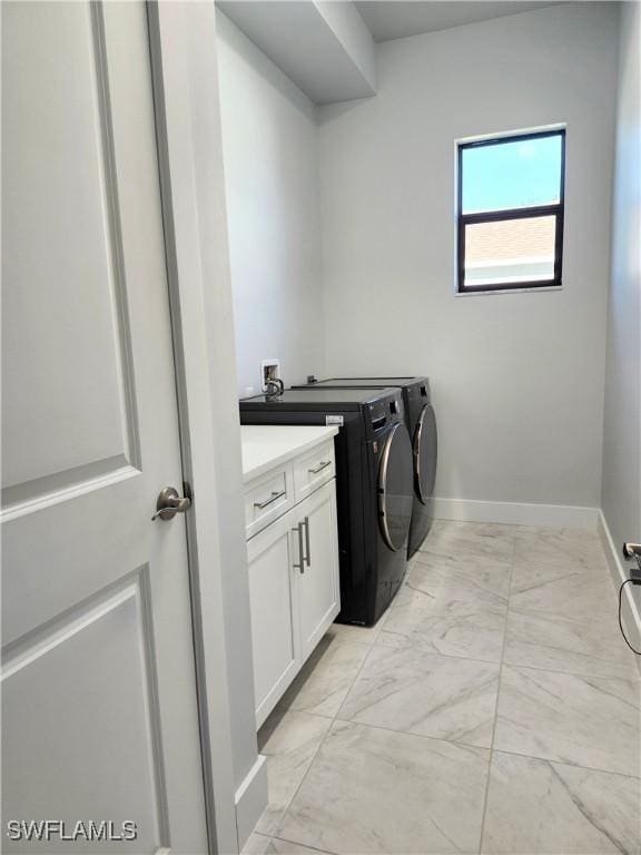 clothes washing area with washing machine and clothes dryer and cabinets