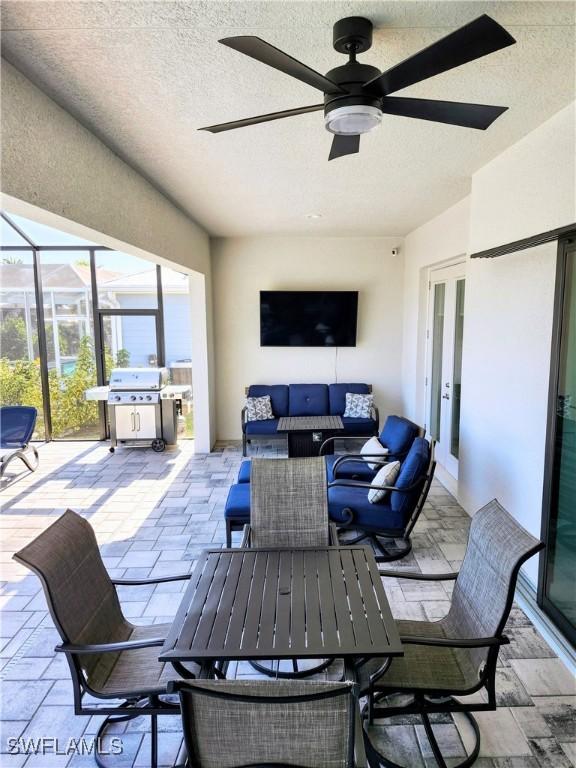 view of patio / terrace with glass enclosure, ceiling fan, area for grilling, and an outdoor living space