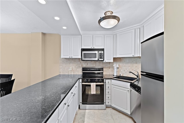 kitchen featuring white cabinetry, sink, stainless steel appliances, dark stone countertops, and decorative backsplash