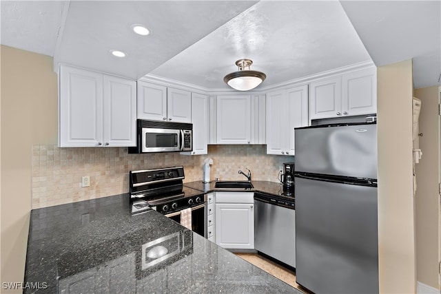 kitchen featuring sink, tasteful backsplash, dark stone counters, white cabinets, and appliances with stainless steel finishes