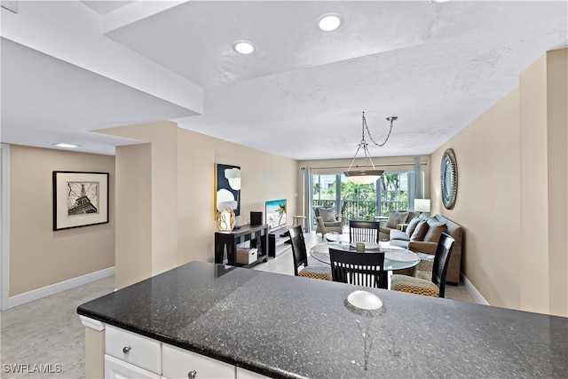 kitchen with white cabinetry, dark stone counters, and decorative light fixtures