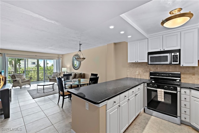 kitchen with white cabinets, appliances with stainless steel finishes, kitchen peninsula, and tasteful backsplash