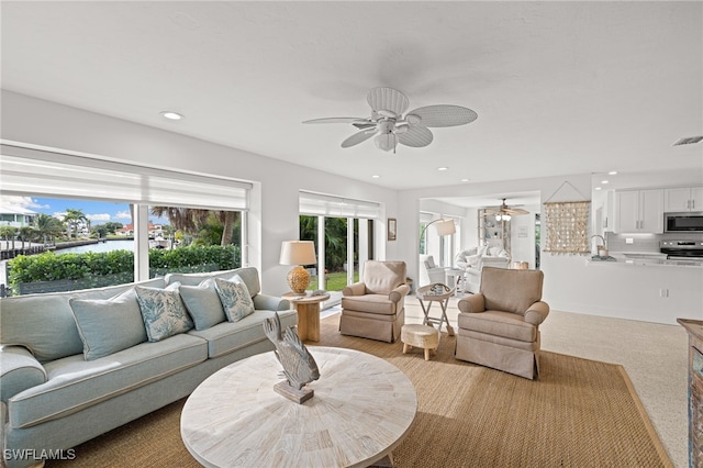 living room with light colored carpet, ceiling fan, and sink